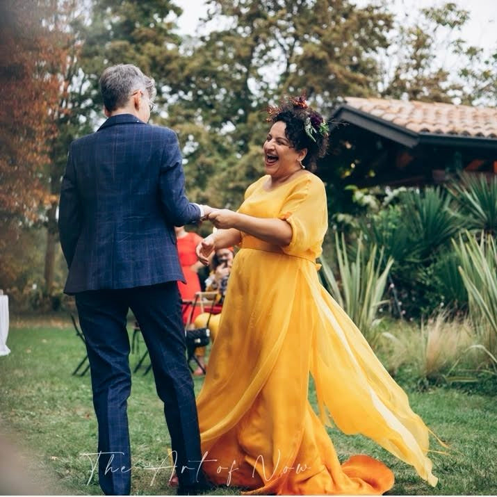 Real LGBTQ+ couple on their wedding day, with one partner wearing a custom-made yellow wedding dress by Larimeloom