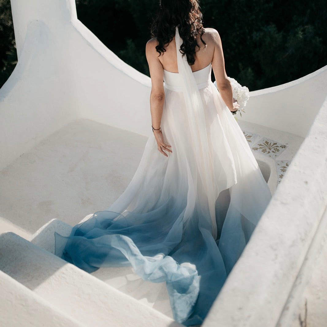 Back view of a bride in a color wedding dress in ivory and sky blue by Larimeloom, walking down an outdoor staircase — inspirational bridal look